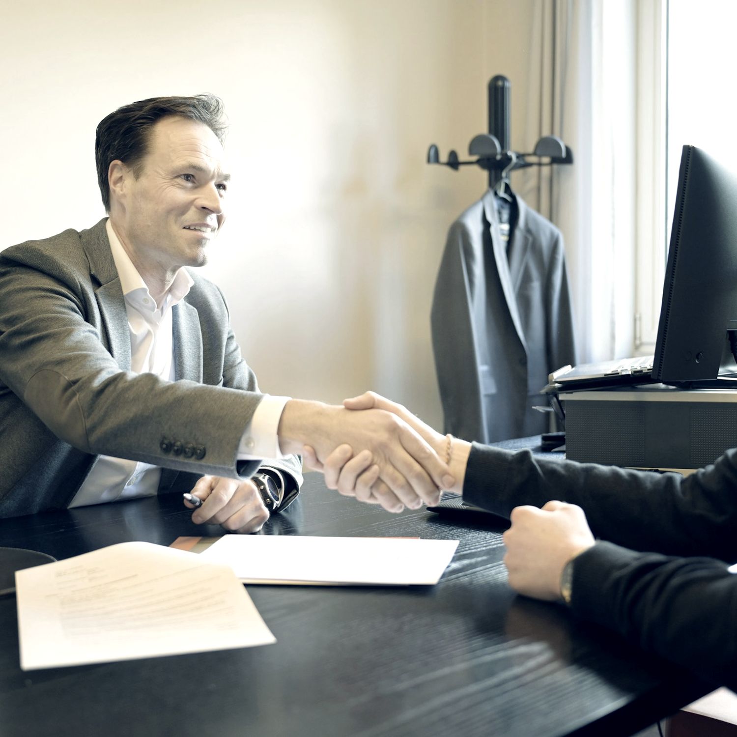 Attorney shaking hands with a client across an office desk